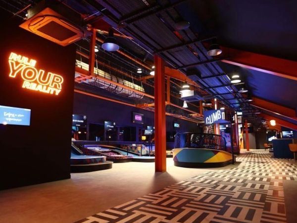 Modern indoor entertainment space with neon signs and vibrant lighting.