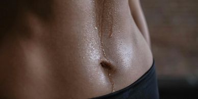 Close-up of a sweaty, toned abdomen with water droplets.