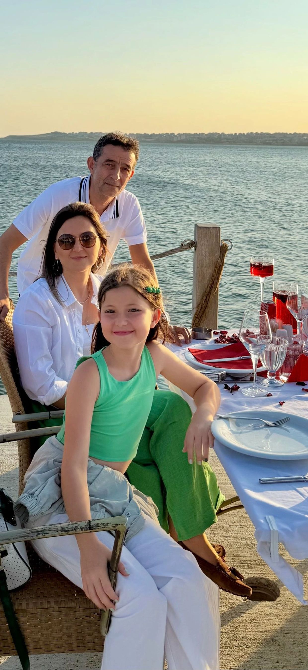 Family enjoying a seaside dinner with smiles and sunset views.