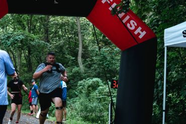 Runners crossing finish line in forest race.