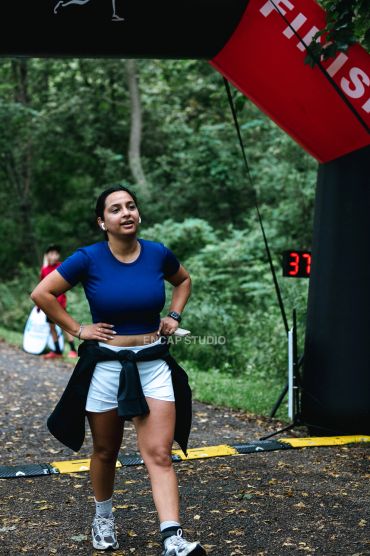 Woman runner catching her breath at the finish line in a forest.