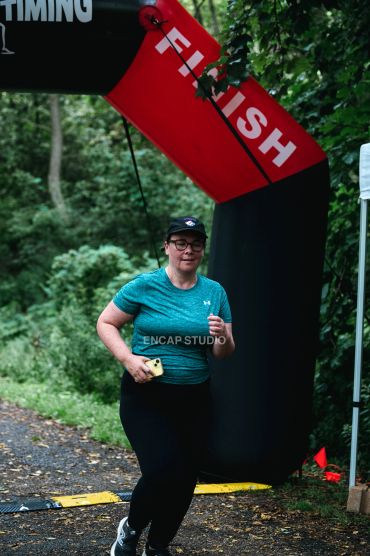 Woman finishing a race outdoors under a finish line banner.