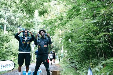Two young men posing in a wooded outdoor setting.