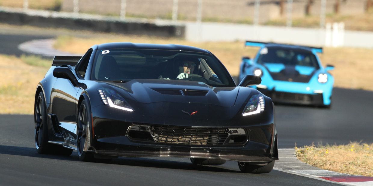 Black sports car leading on a race track with a blue car behind.