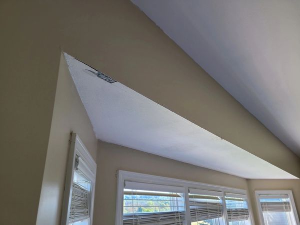 Slanted ceiling with beige walls and windows below.