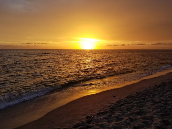 Sunset over a calm beach ocean.