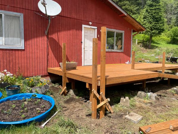 Wooden deck under construction in front of a red house.