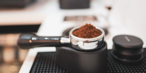 Portafilter filled with ground coffee, ready for espresso.