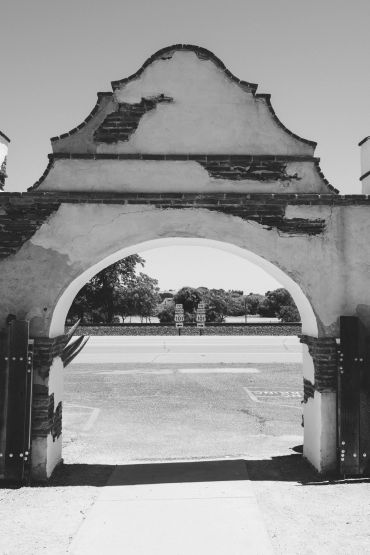 Historic archway with weathered details framing a roadside view.