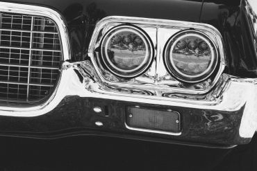 Close-up of vintage car headlights and grille in black and white.