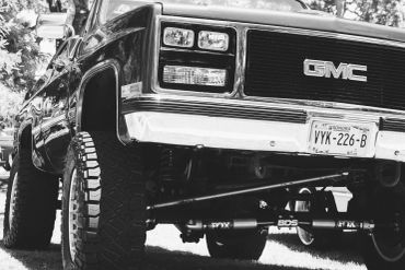 Black and white close-up of a lifted GMC truck with rugged tires.