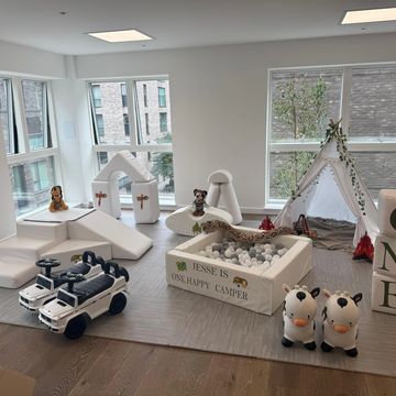 A children's play area with camping-themed toys and decorations in a bright room.