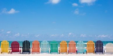Colorful beach chairs lined up on the beach facing the ocean