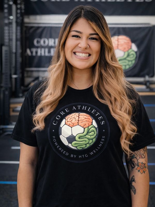 Smiling woman wearing a black Core Athletes t-shirt with a brain and soccer ball design.