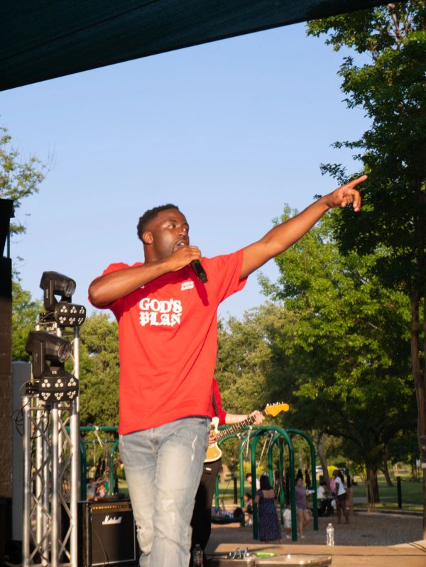 Man in red shirt performing on stage with microphone.