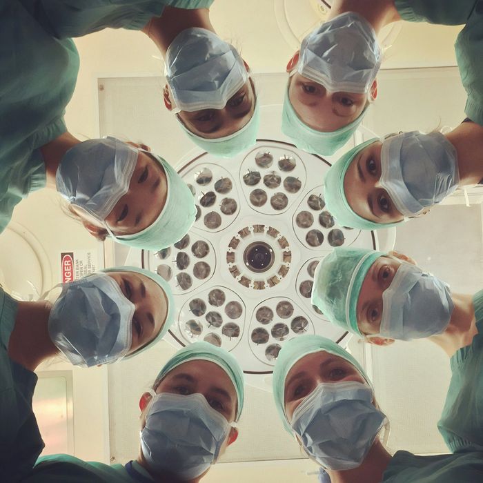 Surgical team in masks and scrubs surrounding the operating table light.