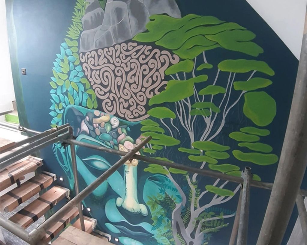 Colorful mural of a face integrated with nature on a stairwell wall.