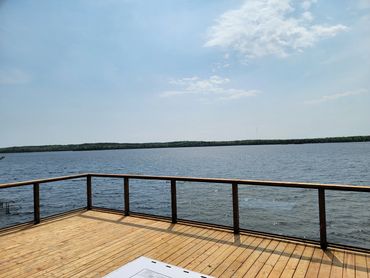 Wooden deck overlooking a calm lake under a clear sky.