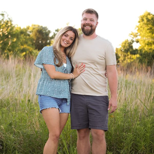 Smiling couple standing in a grassy field.
