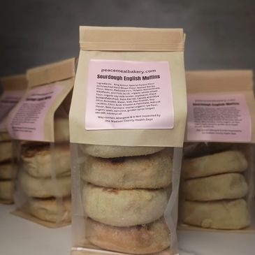 Packages of Sourdough English Muffins with pink labels are stacked.