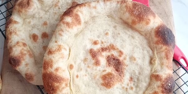 Two pieces of freshly baked flatbread cooling on a rack.