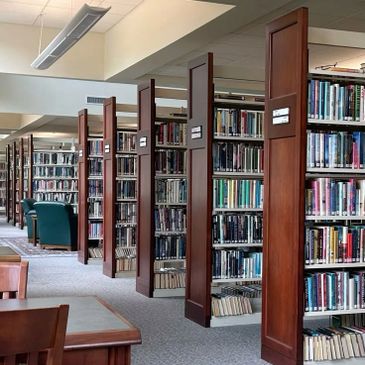 Rows of wooden bookshelves filled with books in a quiet library.