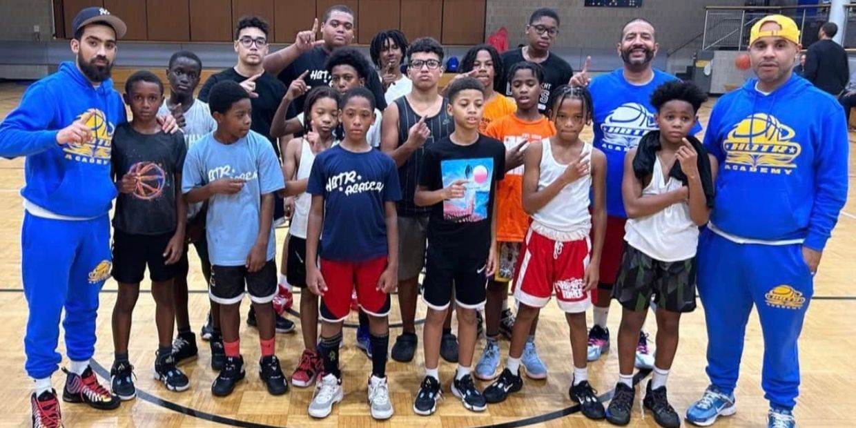 Group of young basketball players and coaches posing in a gym.