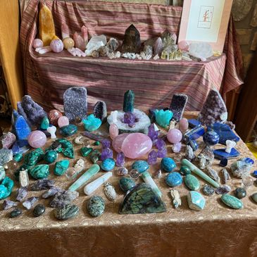 A colorful assortment of polished and raw crystals and stones arranged on fabric.