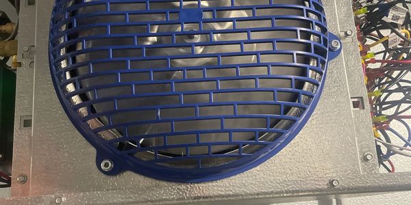 Close-up of a blue protective grille over a computer fan inside a metal casing.
