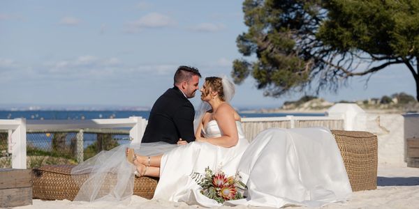 Bride and groom share a tender moment on a beach day.