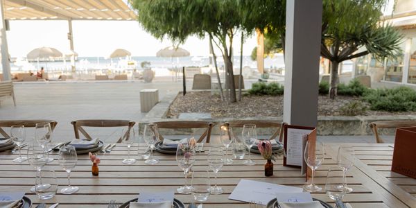 Elegant outdoor dining setup with glassware and napkins at a seaside restaurant.