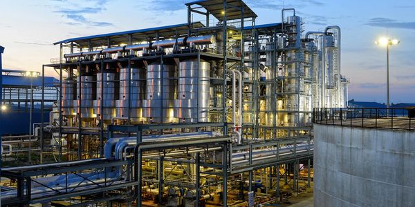 Industrial refinery plant with metal tanks and pipes at dusk.