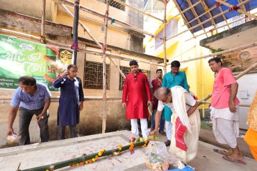 A group paying respects at a decorated grave.