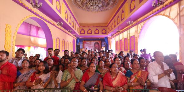 Group of people gathered in prayer inside a decorated hall.