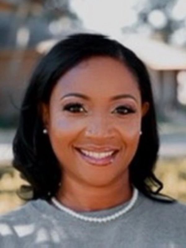 Smiling woman with pearl necklace and natural makeup outdoors.