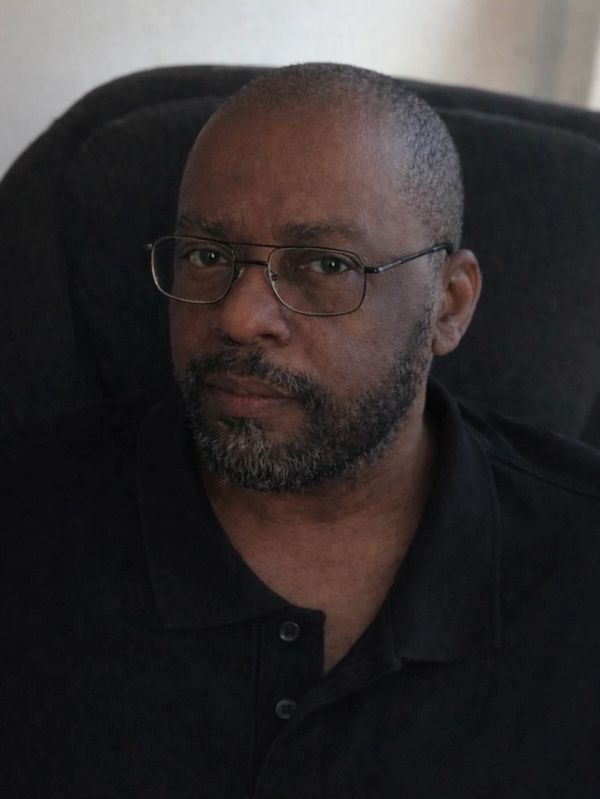 Man with glasses and a beard sitting in a black chair.