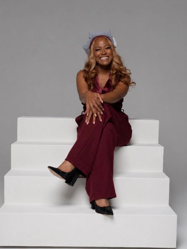 Woman in maroon outfit smiling while sitting on white steps.