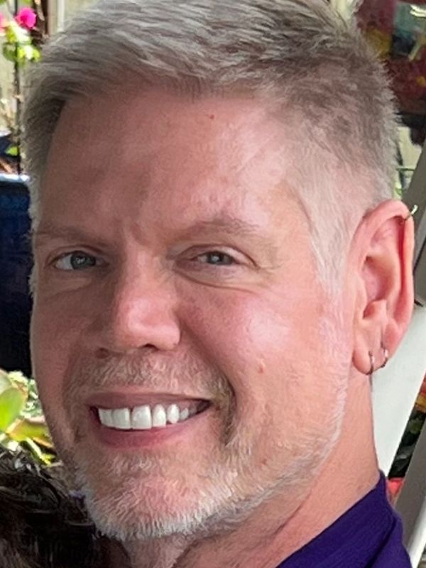 Close-up of a smiling man with light hair and a trimmed beard.