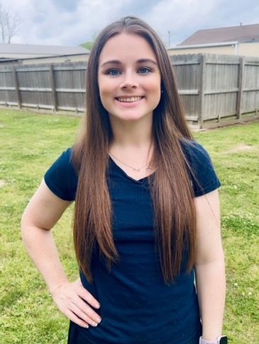 Young woman smiling outdoors with long straight hair.