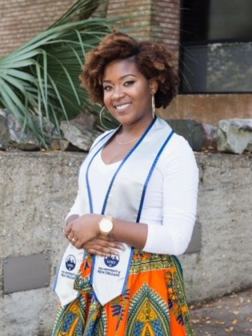 Smiling graduate woman wearing colorful skirt and graduation stole.