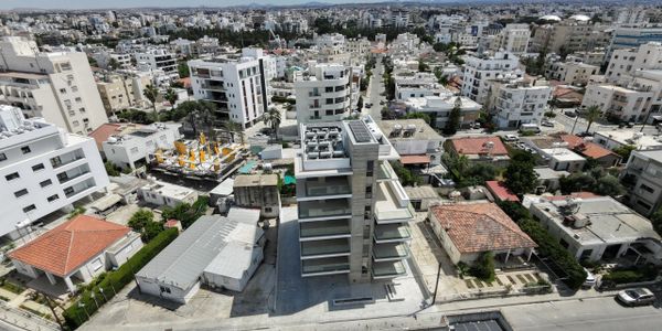 A modern building surrounded by older houses in a dense urban area.