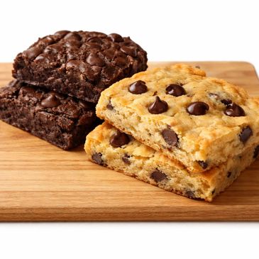 Two chocolate chip blondies and two chocolate brownies on a wooden board.