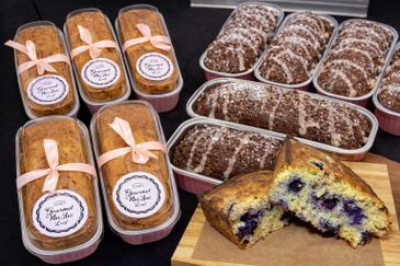 Assorted homemade blueberry and chocolate loaves tied with ribbons and cut to show texture.