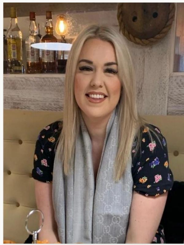 Smiling woman with blonde hair sitting indoors.