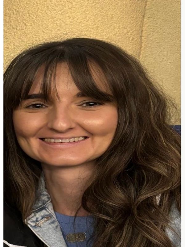 Smiling woman with long brown hair and bangs.
