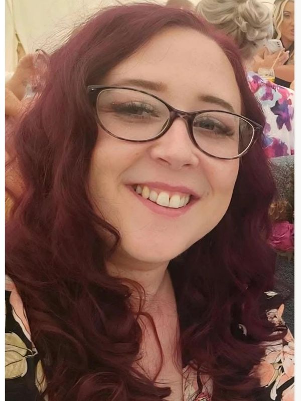 Smiling woman with glasses and curly hair.
