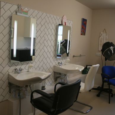 Clean and spacious hairdressing room with two chairs in front of mirrors. In the background there is