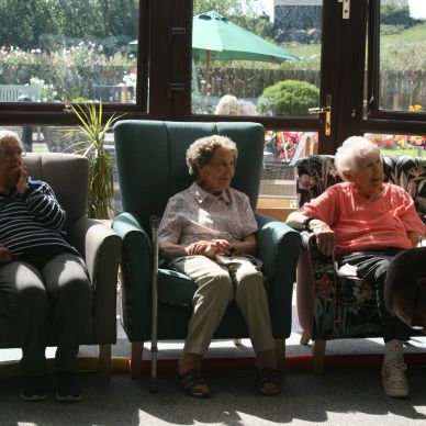 A groups of friends sitting together in a sunny garden room 