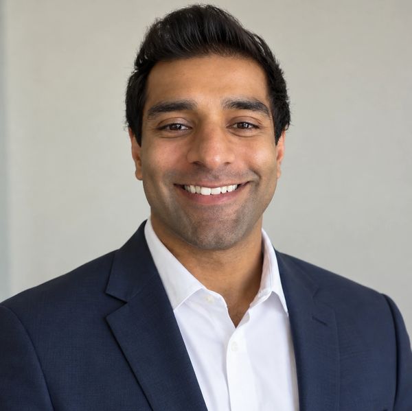 Smiling man in a suit jacket and white shirt.