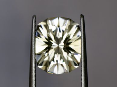 A close-up of a cushion-cut diamond held by tweezers.
